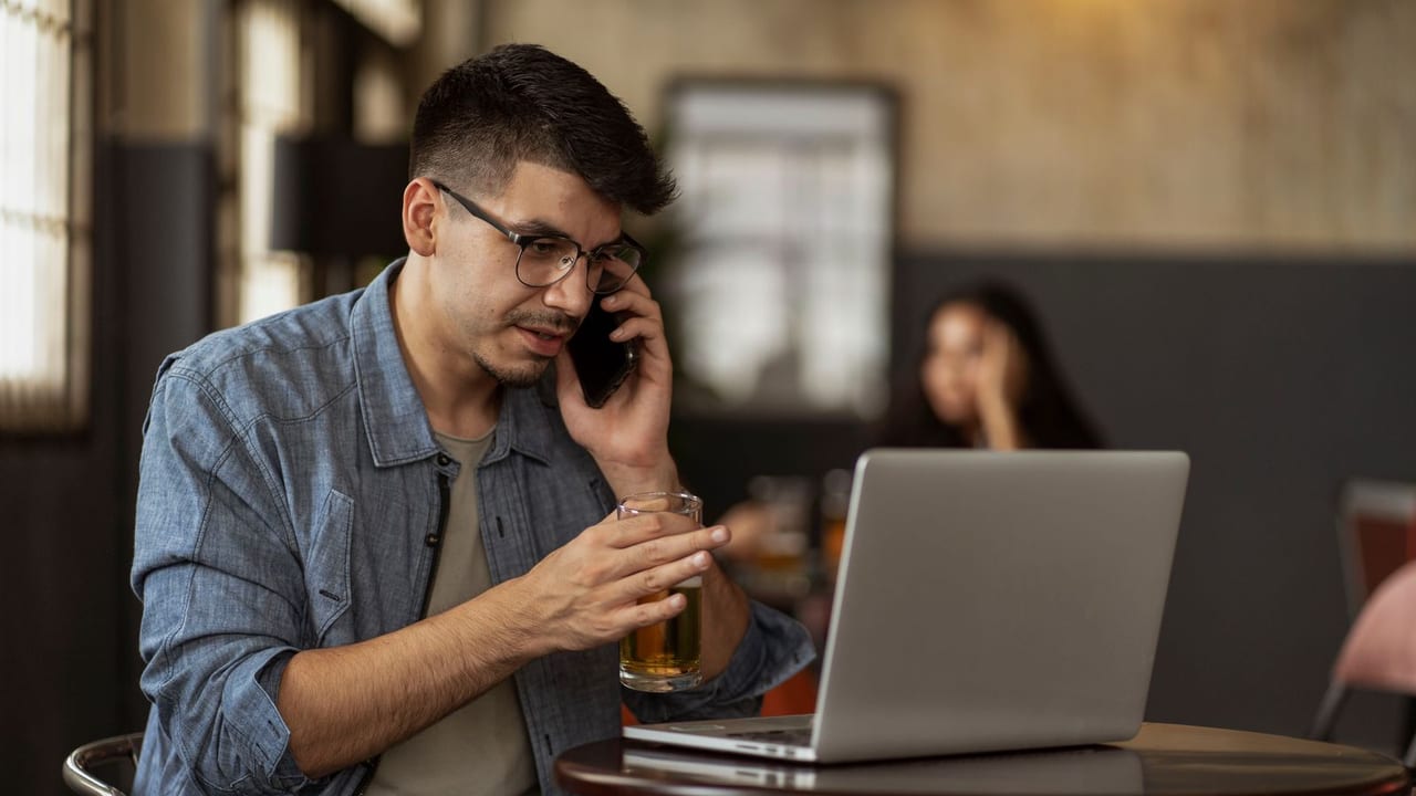 Restaurant owner taking a call at a table with a laptop open in front of him.