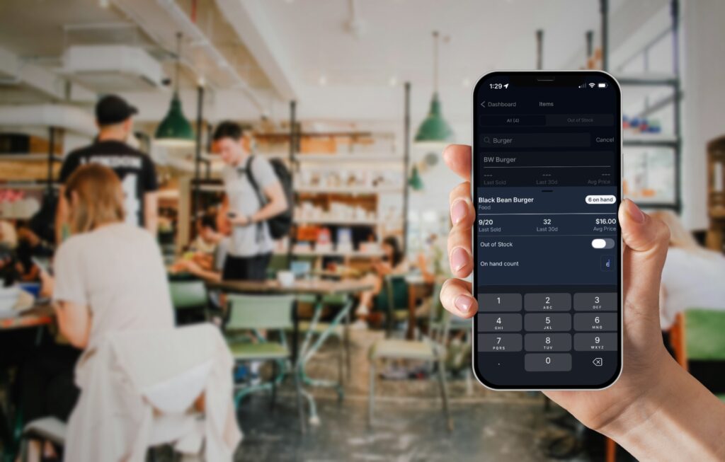 NX_manager_in_restaurant Manager holding their phone in a busy restaurant editing the on hand count of a menu item
